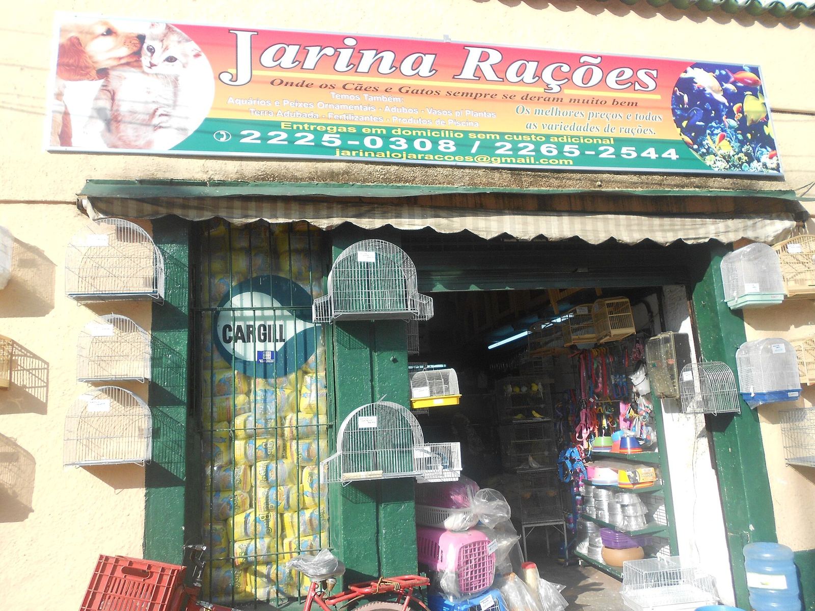 Fachada de loja de rações com gaiolas e sacos na entrada
